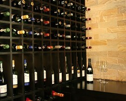 A wine rack with various bottles and a wine glass on a counter.