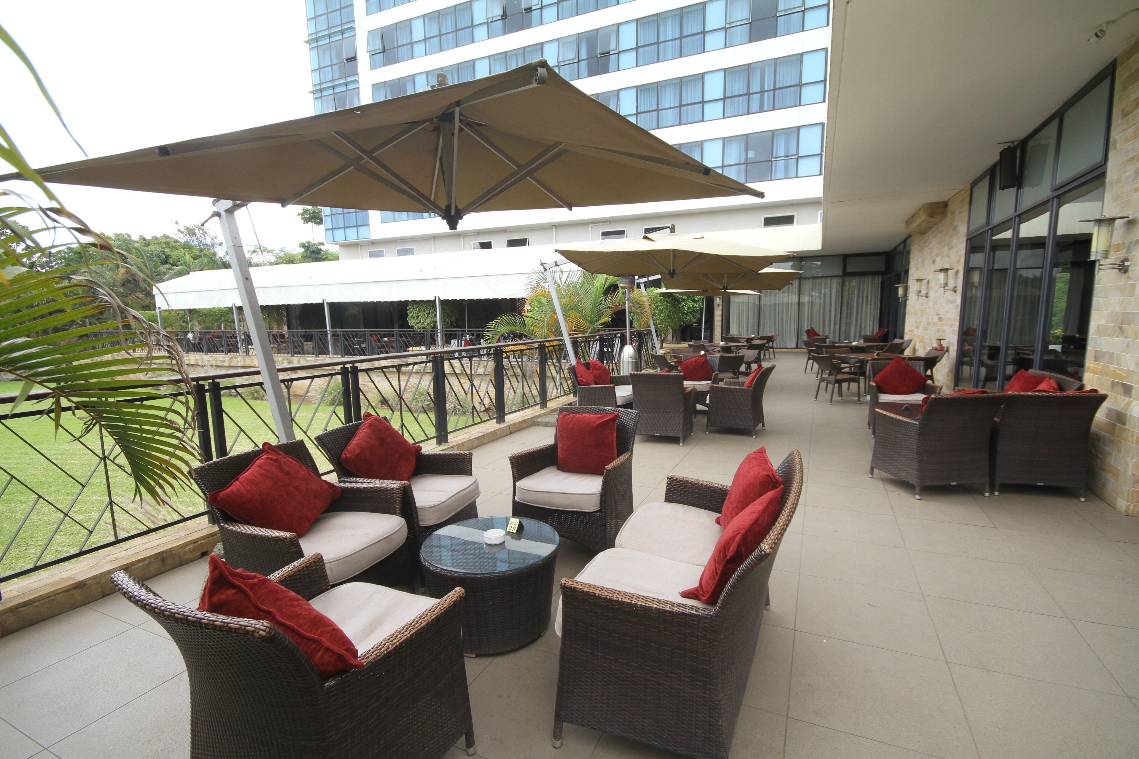 An outdoor patio with wicker furniture, red cushions, and large umbrellas.