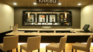 A bar area with a sign reading "KARIBU," bar stools, and a counter with bottles and glasses. - Mount Meru Hotel (Arusha)