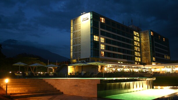 A multi-story hotel with a pool area, outdoor seating, and a waterfall feature. - Mount Meru Hotel (Arusha)