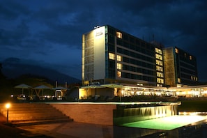 A multi-story hotel with a pool area, outdoor seating, and a waterfall feature. - Mount Meru Hotel (Arusha)