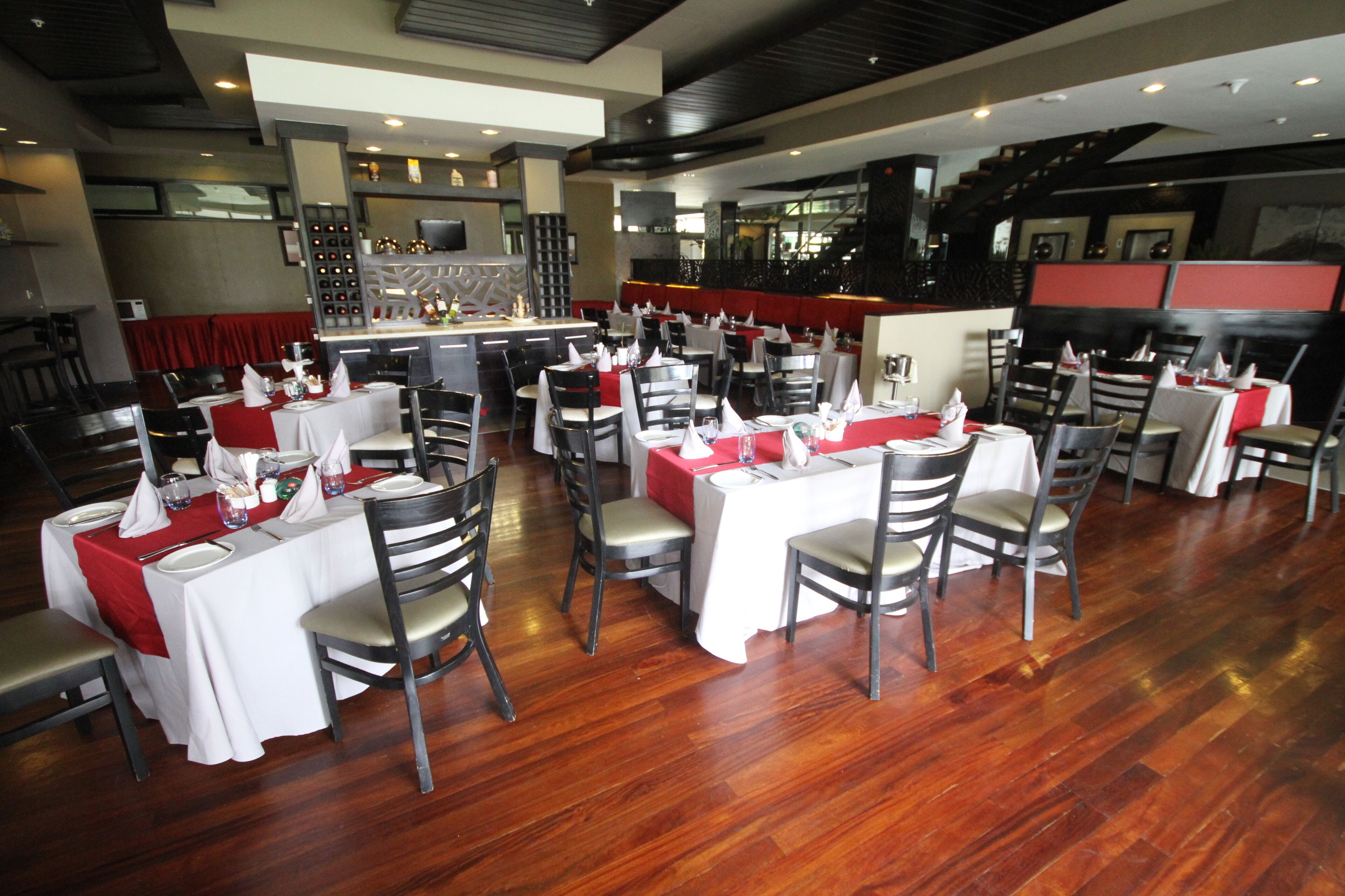 Un restaurante con varias mesas dispuestas para comer, una zona de bar y una decoración de estilo moderno.