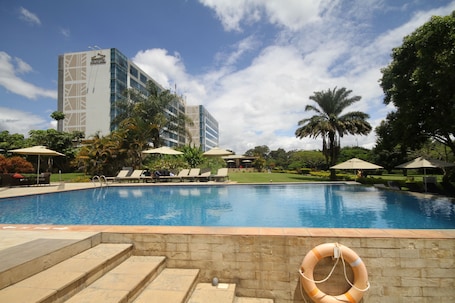 Una piscina al aire libre, sombrillas, sillones reclinables de piscina