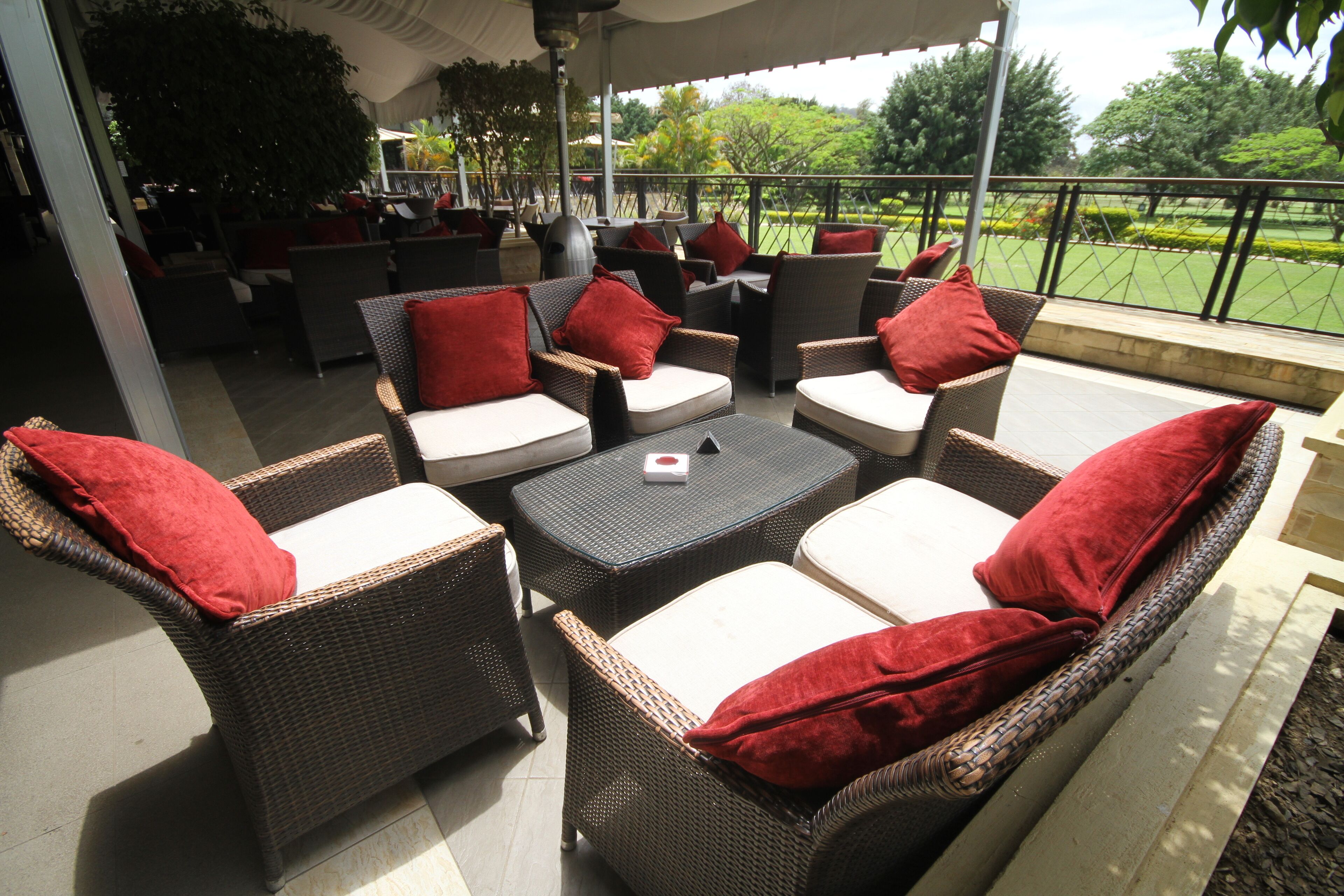 An outdoor patio area with wicker furniture and red cushions.