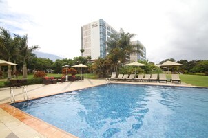Una piscina al aire libre, sombrillas, sillones reclinables de piscina