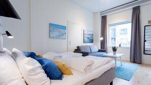 A modern hotel room with a large bed, a sofa, a small table with a plant, and two paintings on the wall. - ApartDirect Hammarby Sjöstad (Stockholm)