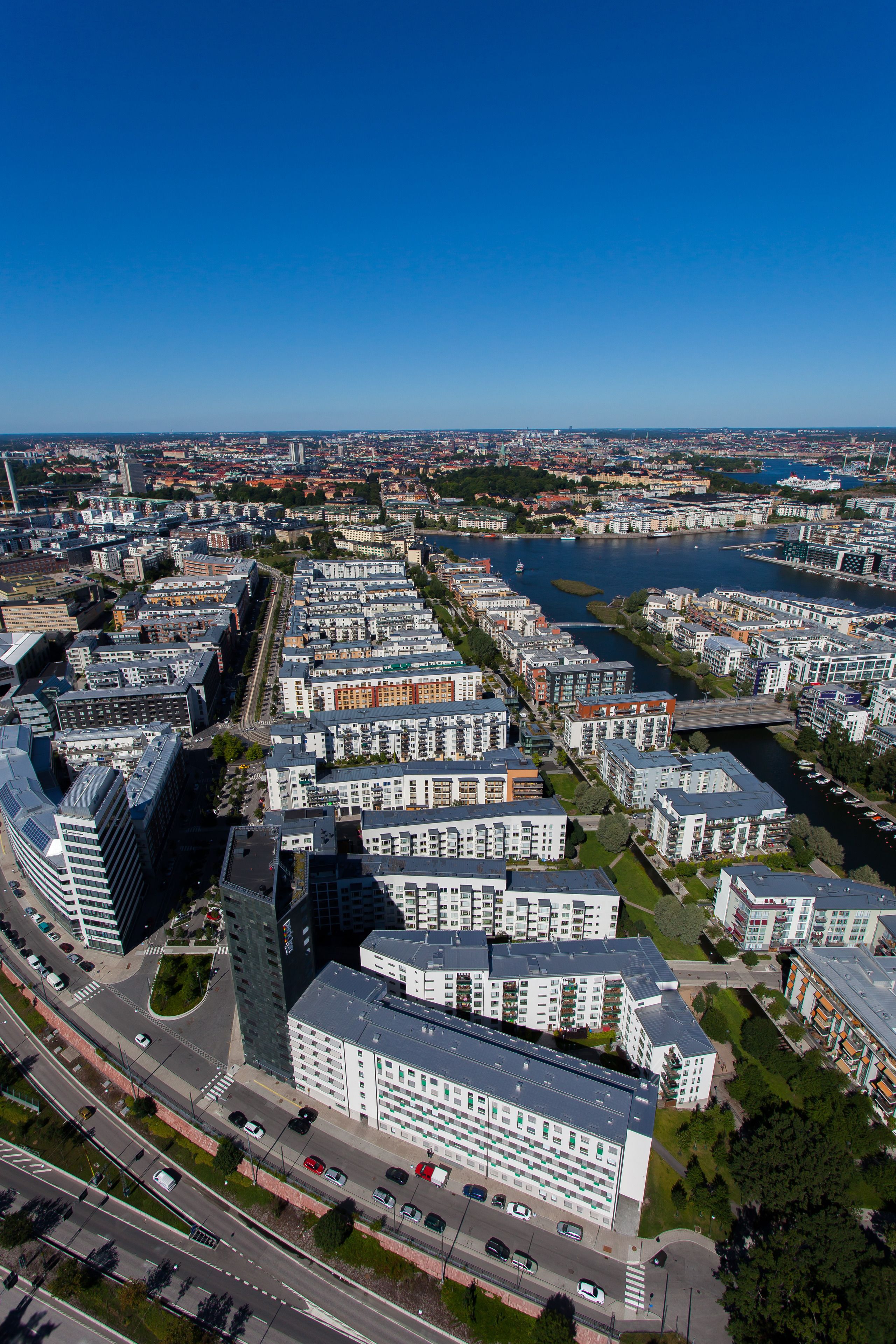 An aerial view of a modern urban area with high-rise residential buildings, a river, and a bridge.