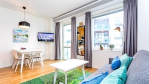 A modern living room with a white table, grey sofa, and a green patterned rug. - ApartDirect Hammarby Sjöstad (Stockholm)