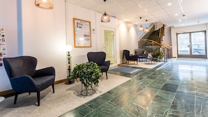 A spacious lobby with modern furniture, a staircase, and a reception desk. - ApartDirect Hammarby Sjöstad (Stockholm)