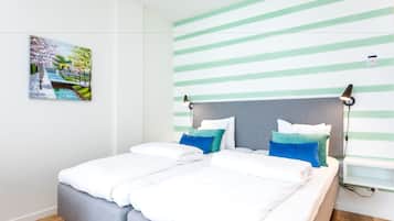 A modern bedroom with a bed, pillows, a headboard, a painting, and a striped wall.