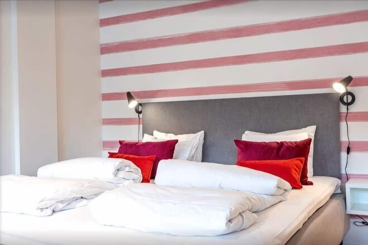 A hotel room with a bed, pillows, and a headboard.