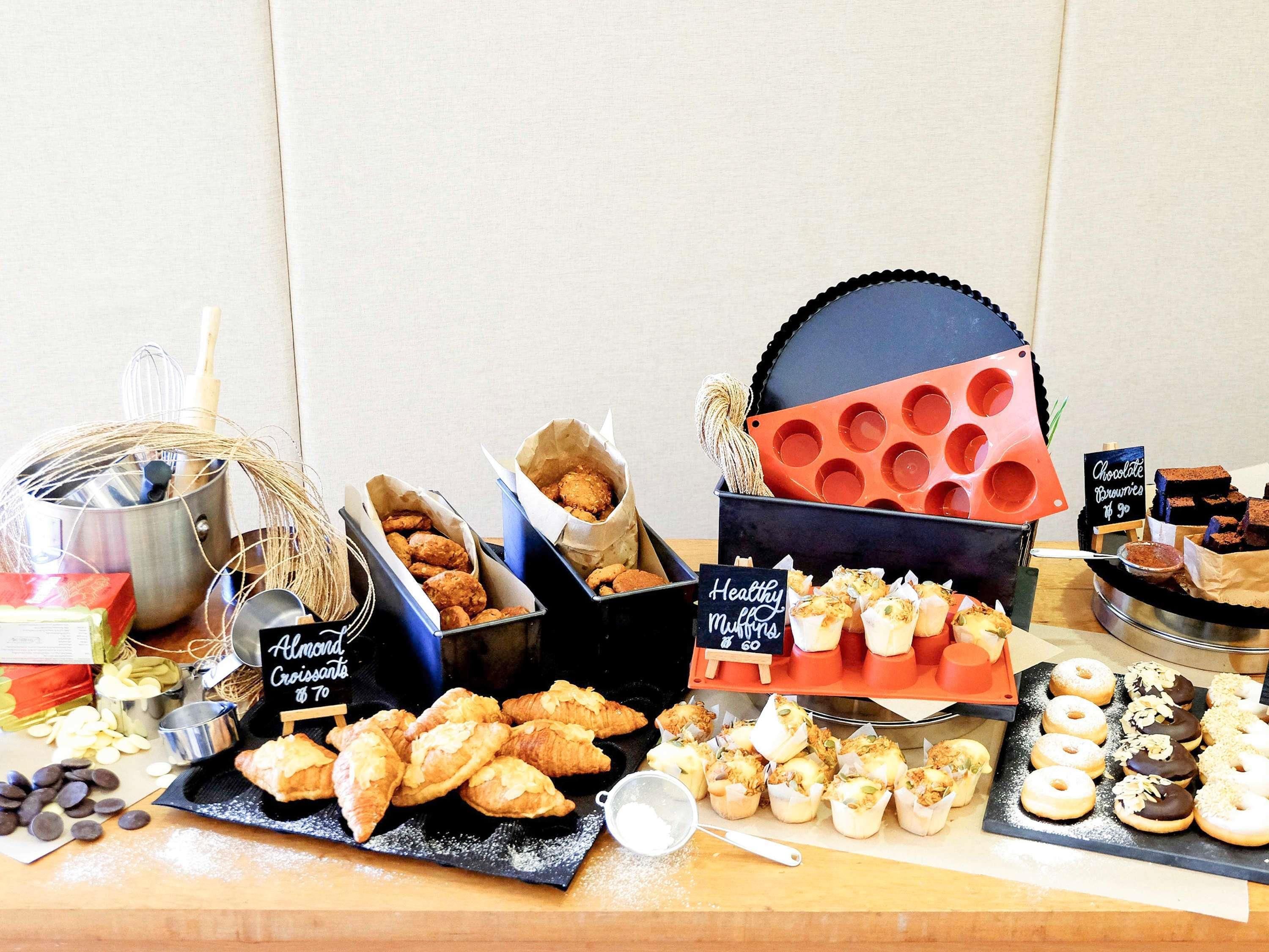 Une variété de produits de boulangerie était exposée sur une table, notamment des muffins, des croissants et des beignets.