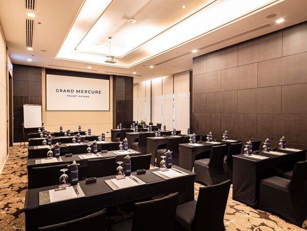 A conference room with multiple tables, chairs, and a large screen displaying 'GRAND MERCURY PHUKET PATONG'. - Grand Mercure Phuket Patong (Patong)