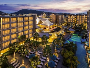 A hotel with multiple floors, a swimming pool, and outdoor seating areas.