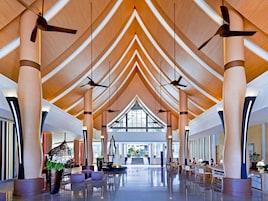 Un amplio hall con techos altos, columnas grandes y ventiladores de techo.
