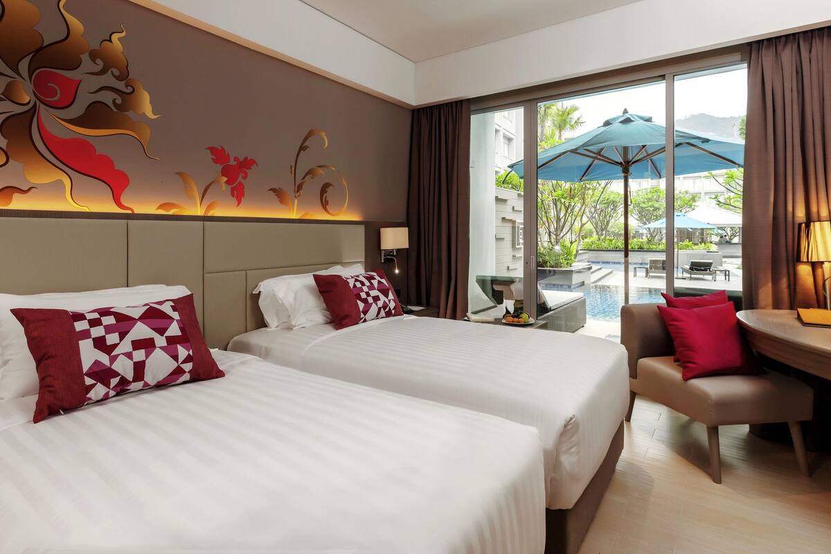 Une chambre d’hôtel avec deux lits, un canapé, une table et une vue sur une piscine et un espace verdoyant.
