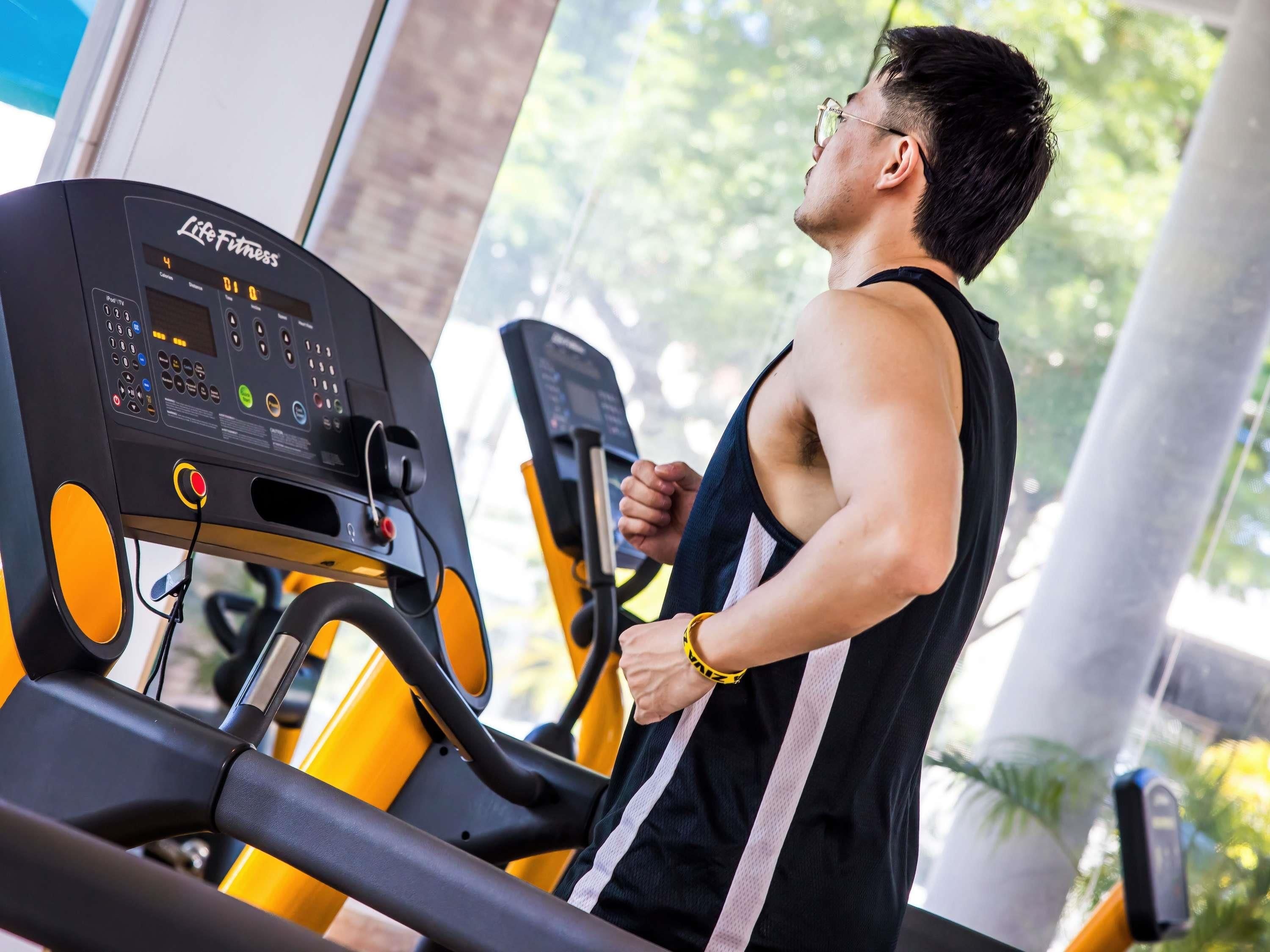 Una persona usando una cinta de correr en un gimnasio con vista a la ventana.