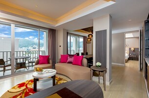 Una habitación de hotel moderna con sofá, mesa de comedor y balcón con vista a la ciudad.