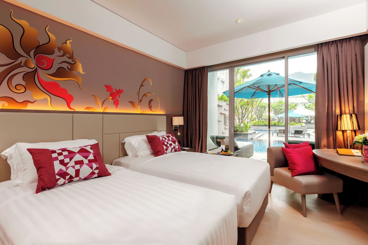A hotel room with two beds, a dining area, and a view of the outdoors.