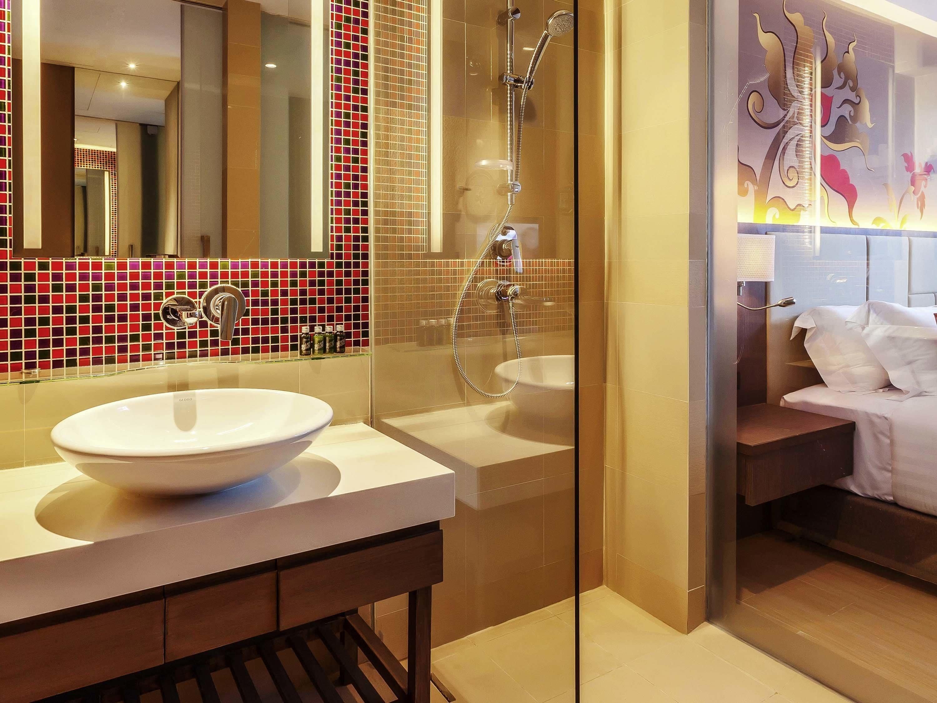 Une salle de bain moderne avec un grand miroir, deux lavabos, une douche et un lit.