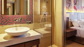 Une salle de bain moderne avec un grand miroir, deux lavabos, une douche et un lit.