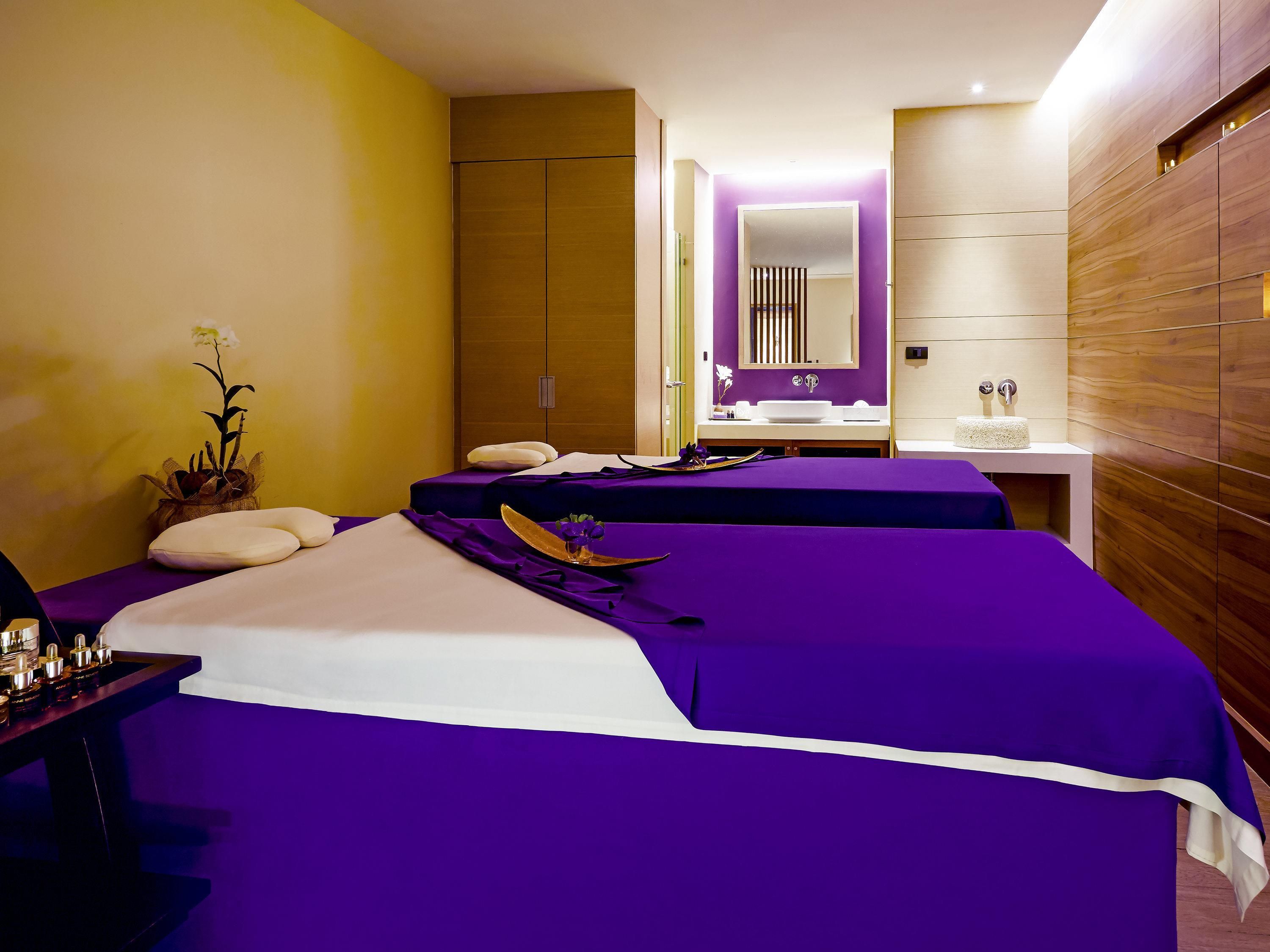 A hotel room with two beds, a bathroom, and a small sitting area.