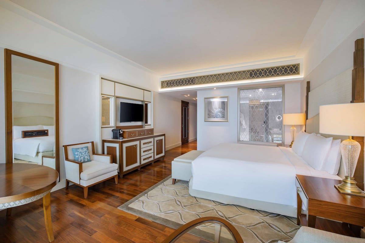 A hotel room with a large bed, a TV, a desk, and a chair.