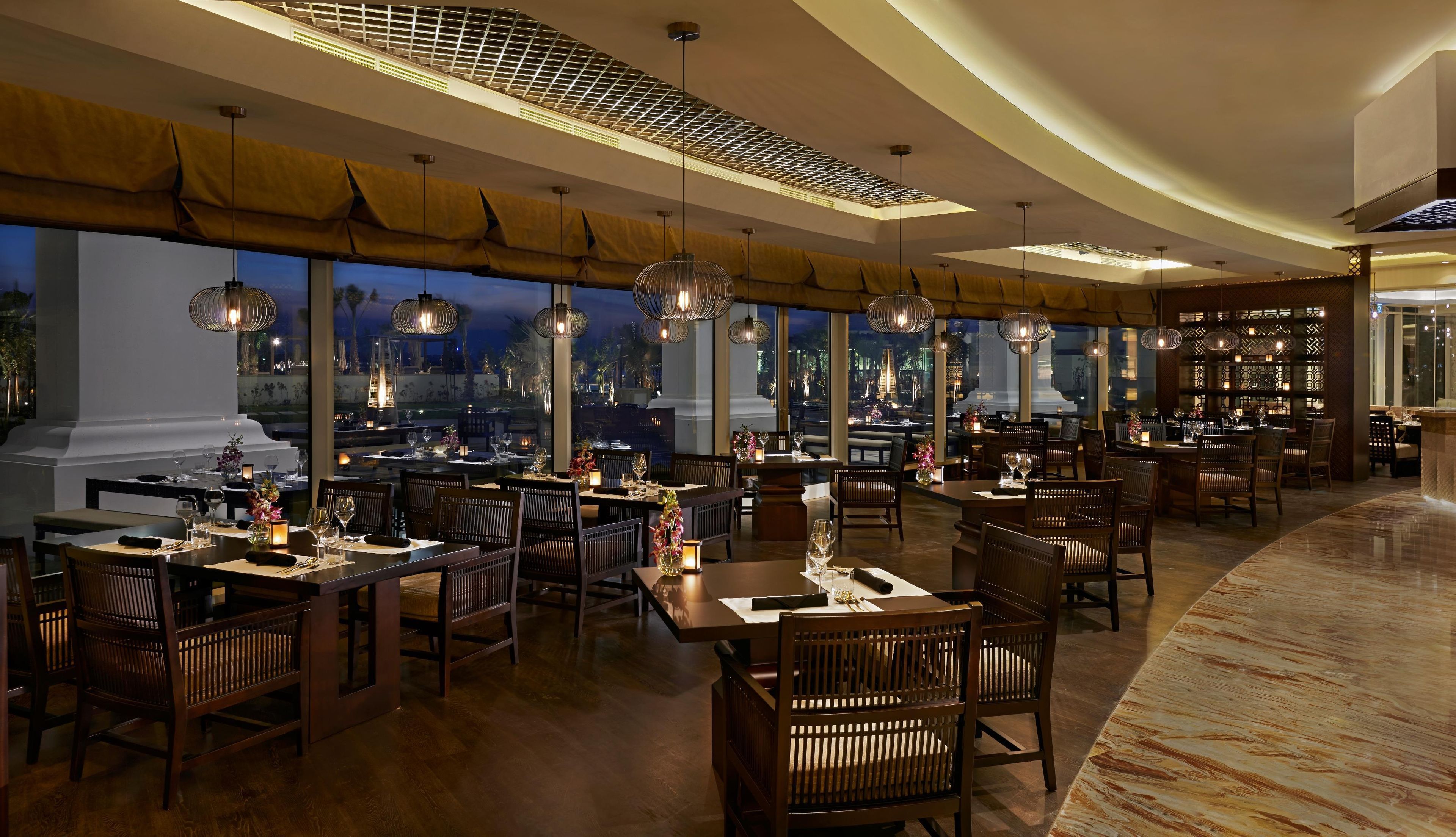 Un restaurante con varias mesas, sillas e iluminación colgante.