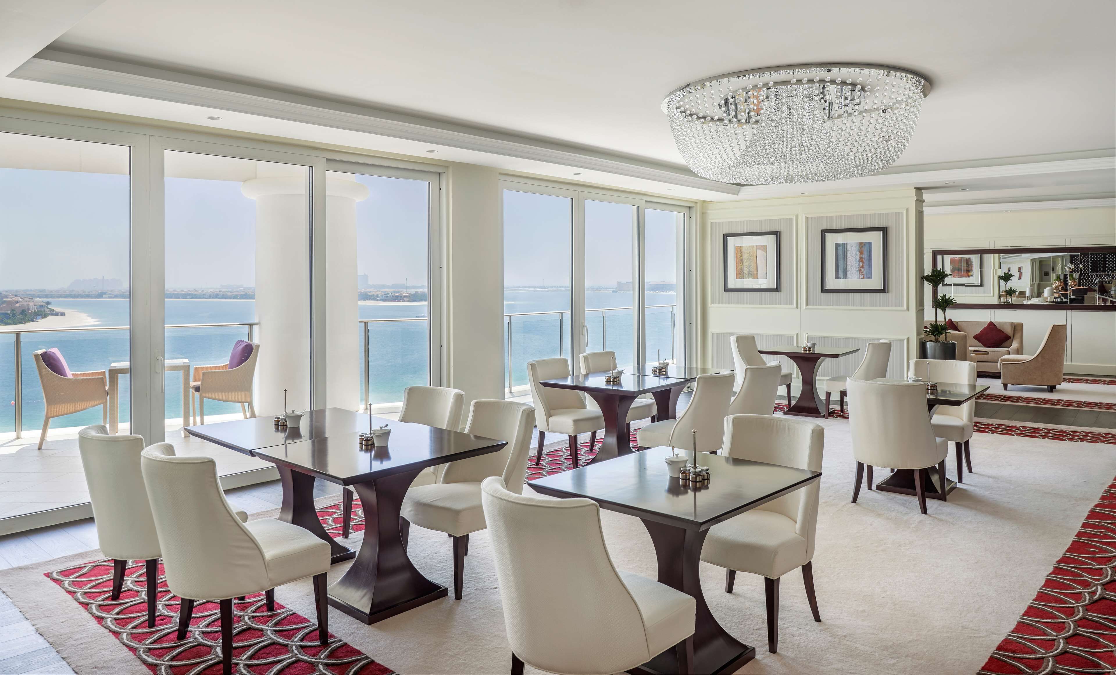 A spacious dining area with a view of the sea, large windows, and a chandelier.