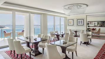 A spacious dining area with a view of the sea, large windows, and a chandelier.