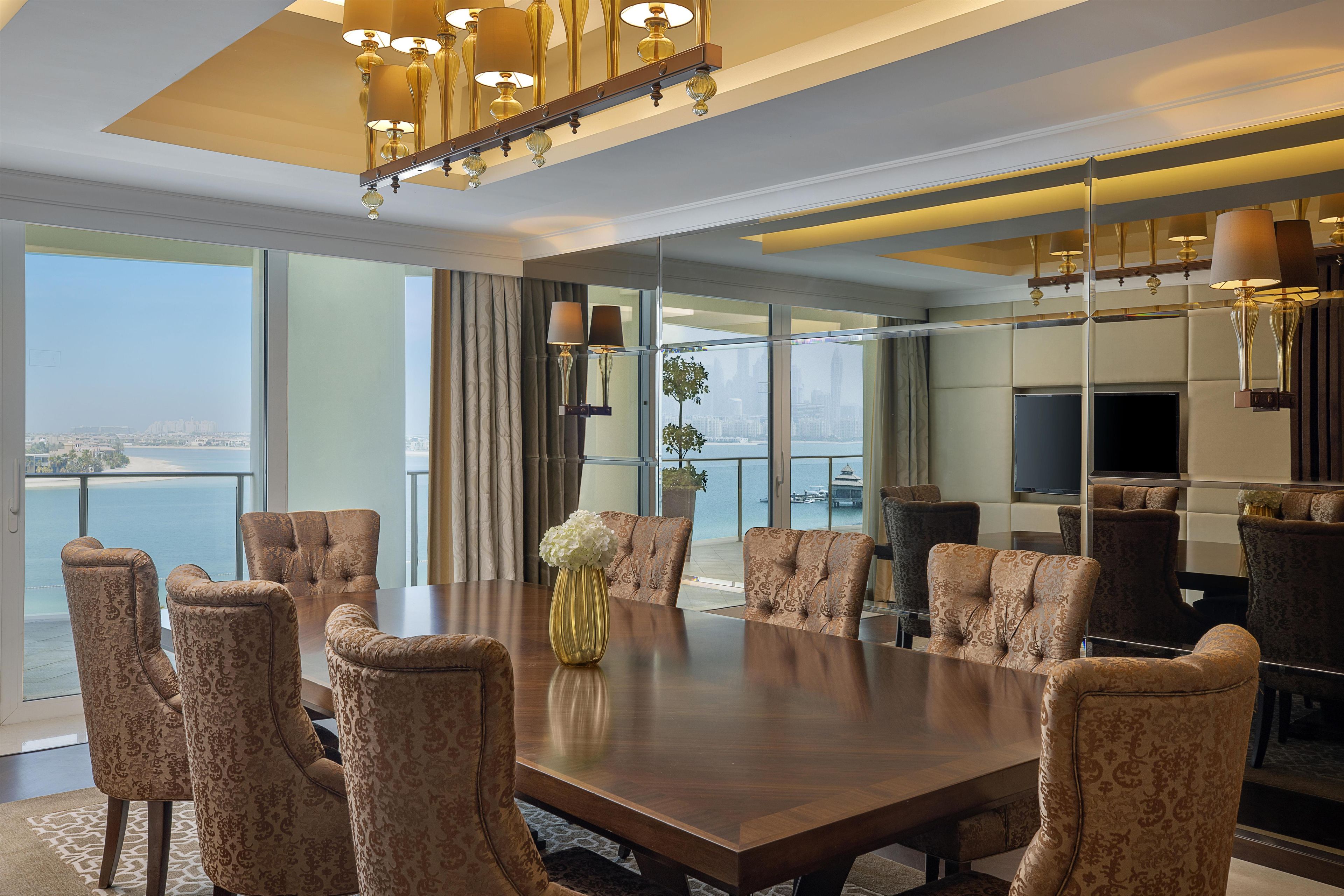 A spacious conference room with a large table, multiple chairs, and a view of the cityscape through large windows.