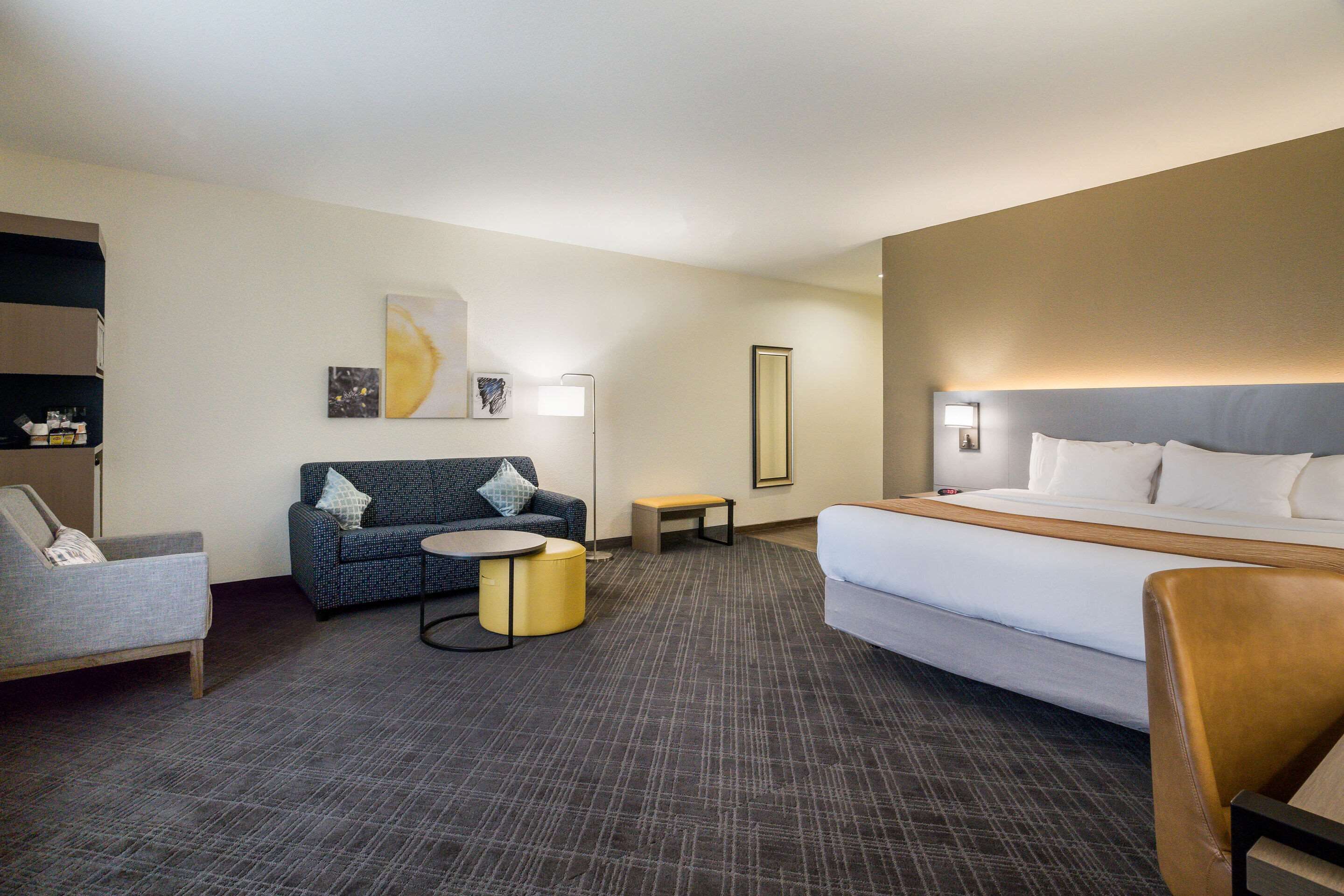 Una habitación de hotel con una cama, un sofá, una mesita redonda y una silla.