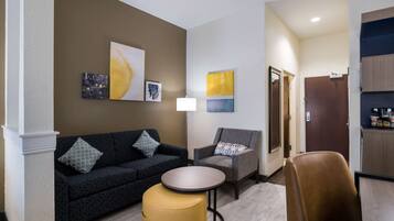 A hotel lobby with a sofa, armchair, small round table, and artwork on the walls.