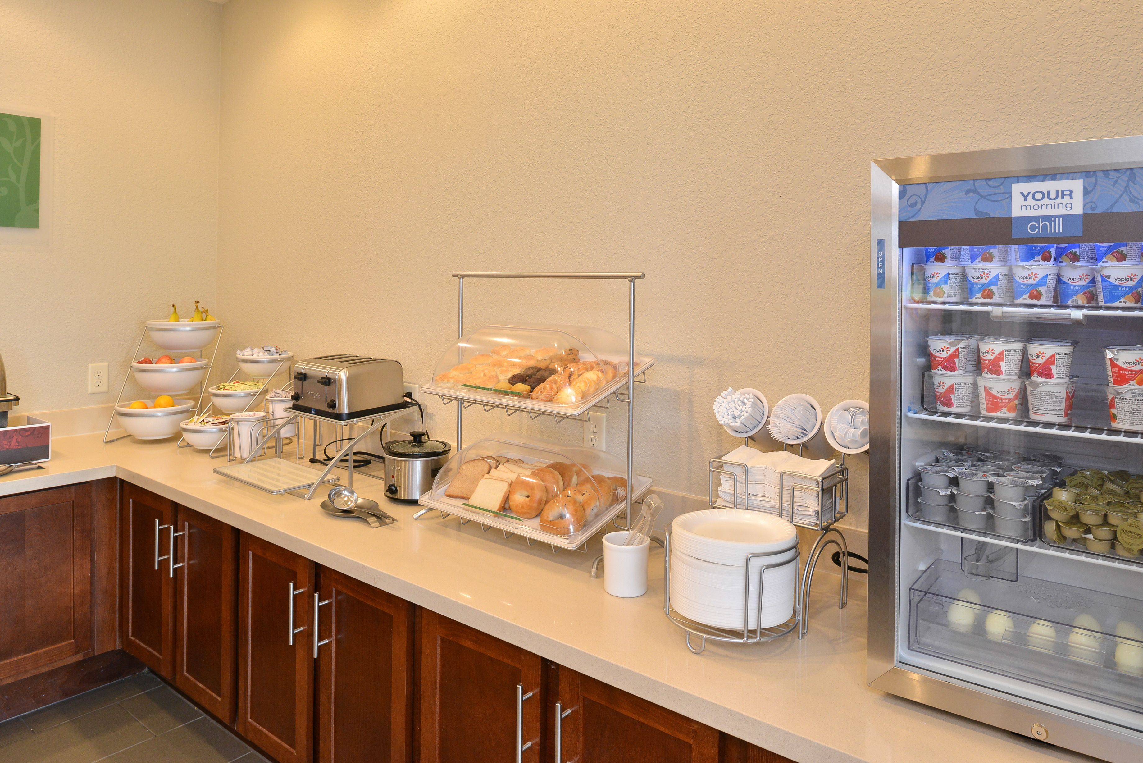 A breakfast buffet with various food items and a refrigerator labeled "YOUR morning chill".