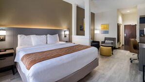 Ein Hotelzimmer mit einem großen Bett, Nachttischen, einem Schreibtisch, einem Sessel und einer Couch.