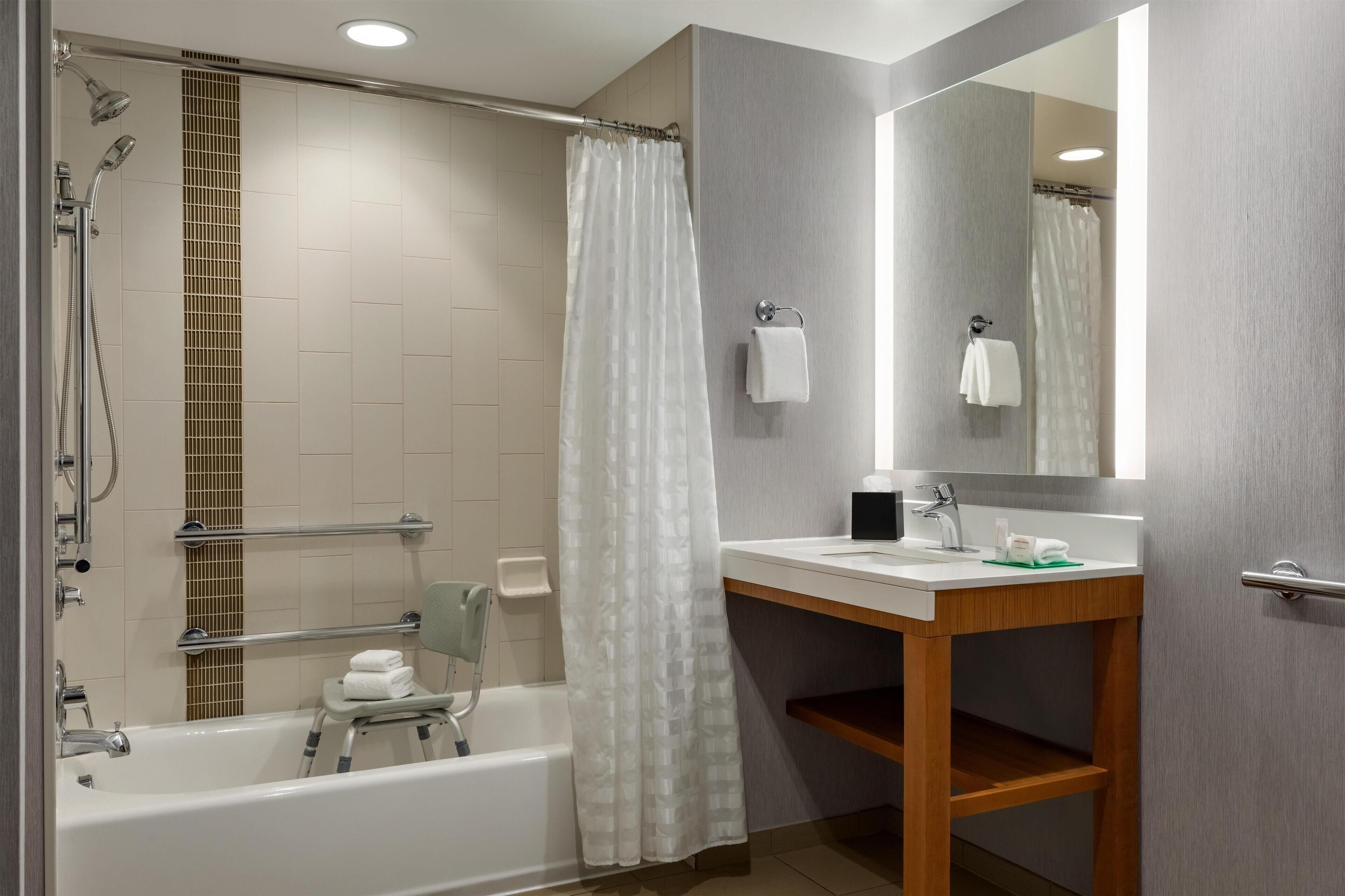 A modern bathroom with a bathtub, shower, and vanity.