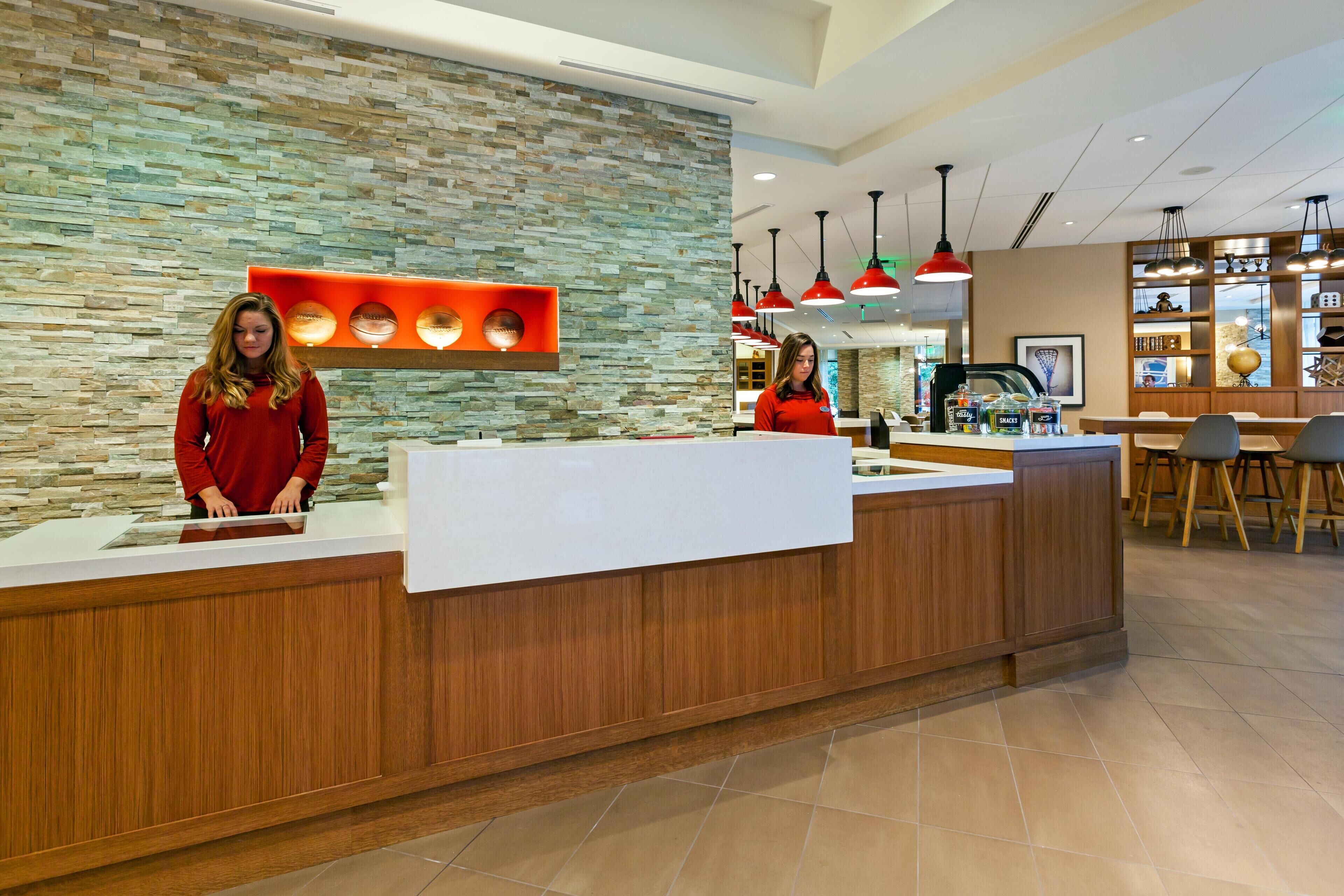 A reception area with a wooden counter, a stone wall, and a seating area with tables and chairs.