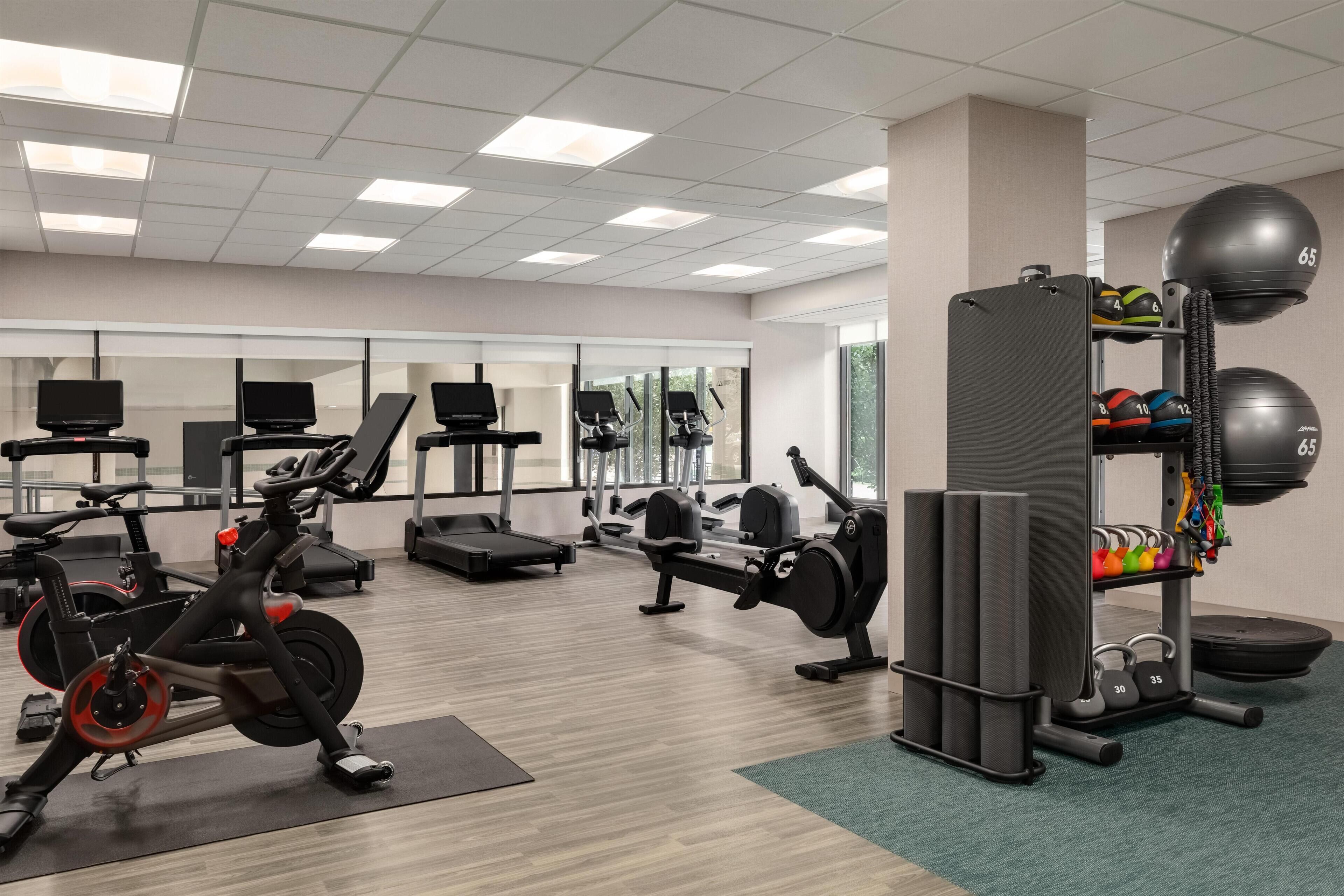 A gym with exercise equipment, weight racks, and a mirror wall.