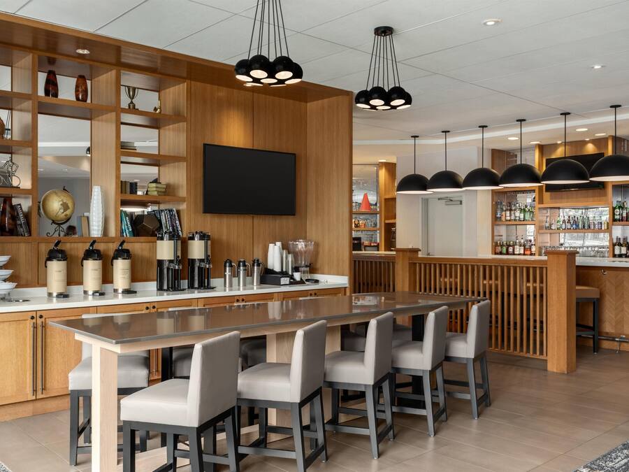A modern kitchen with a central island, wooden shelving, and a bar area with a variety of bottles.