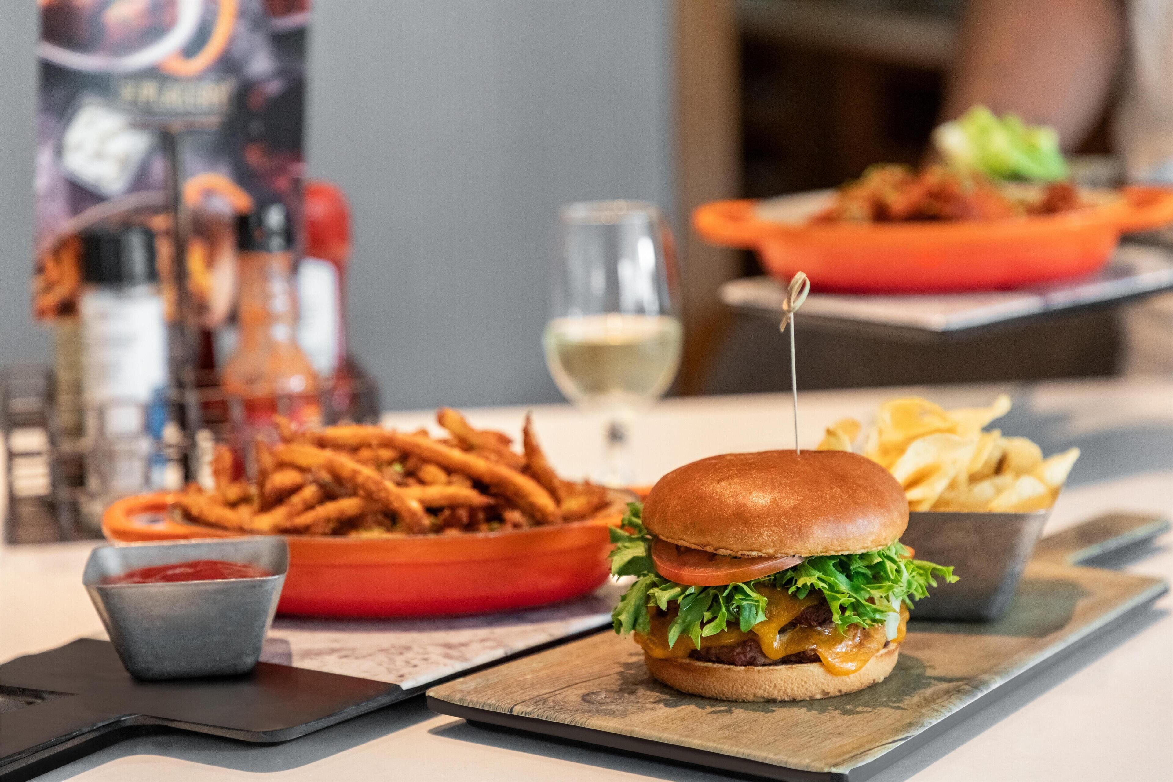 A burger with fries and ketchup on a wooden board.