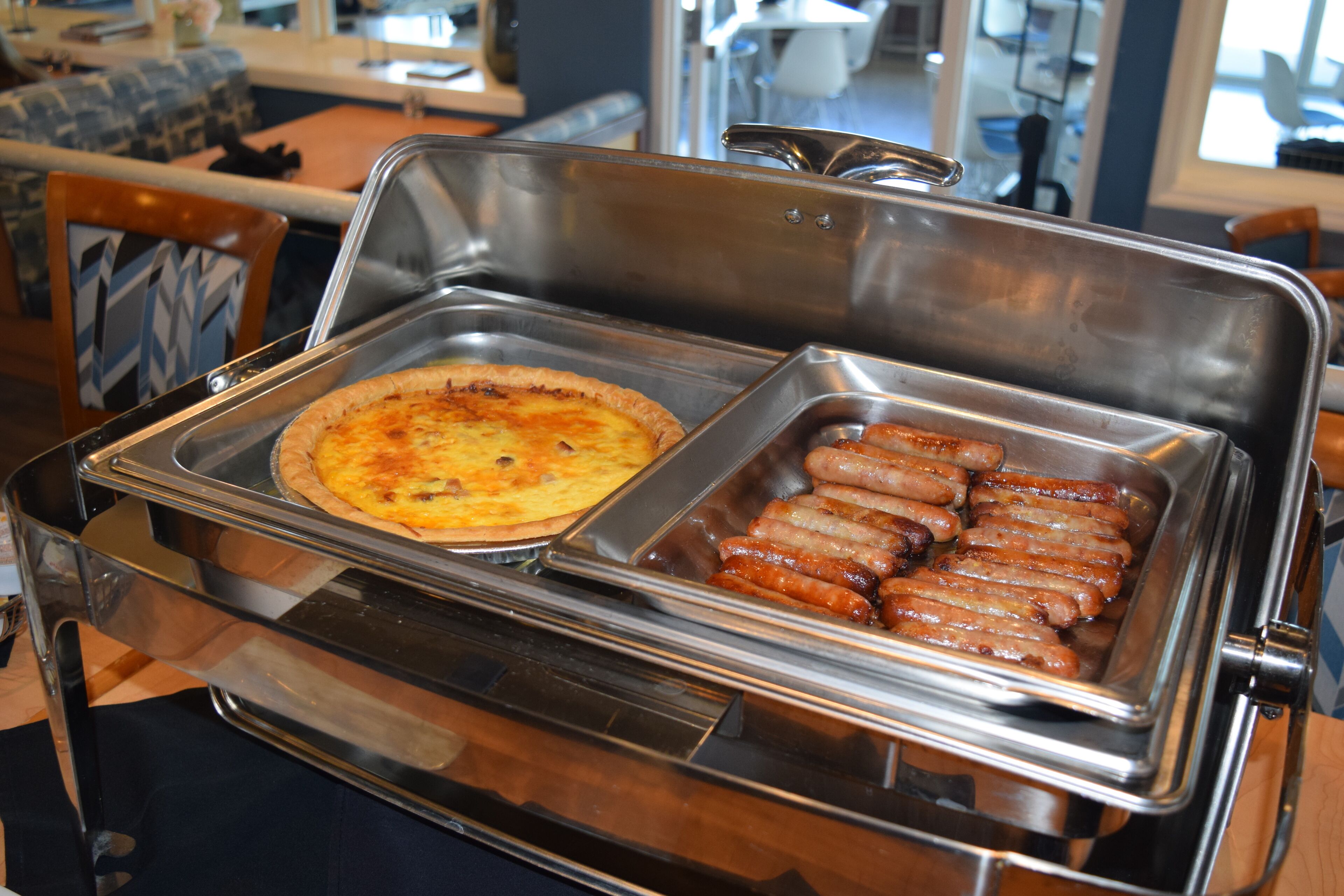 A buffet with a pizza and sausages.