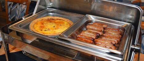 A buffet with a pizza and sausages.