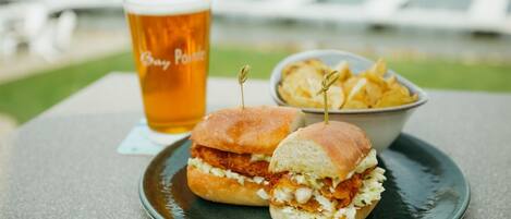 Un panino con patatine fritte e una birra in un bicchiere su un tavolo con vista sull'acqua.