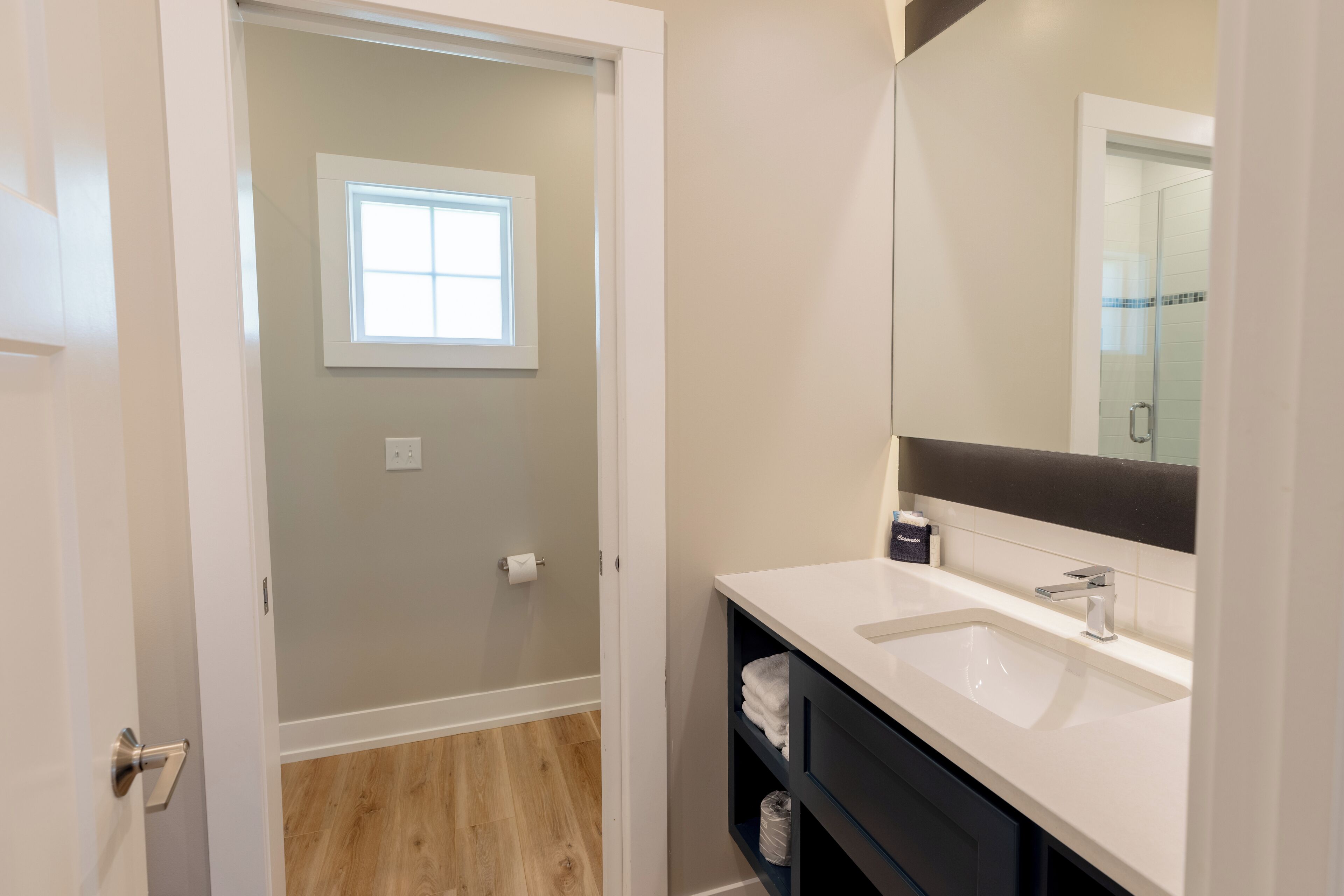 Un baño moderno con un lavamanos blanco, tocador oscuro y un espejo grande.