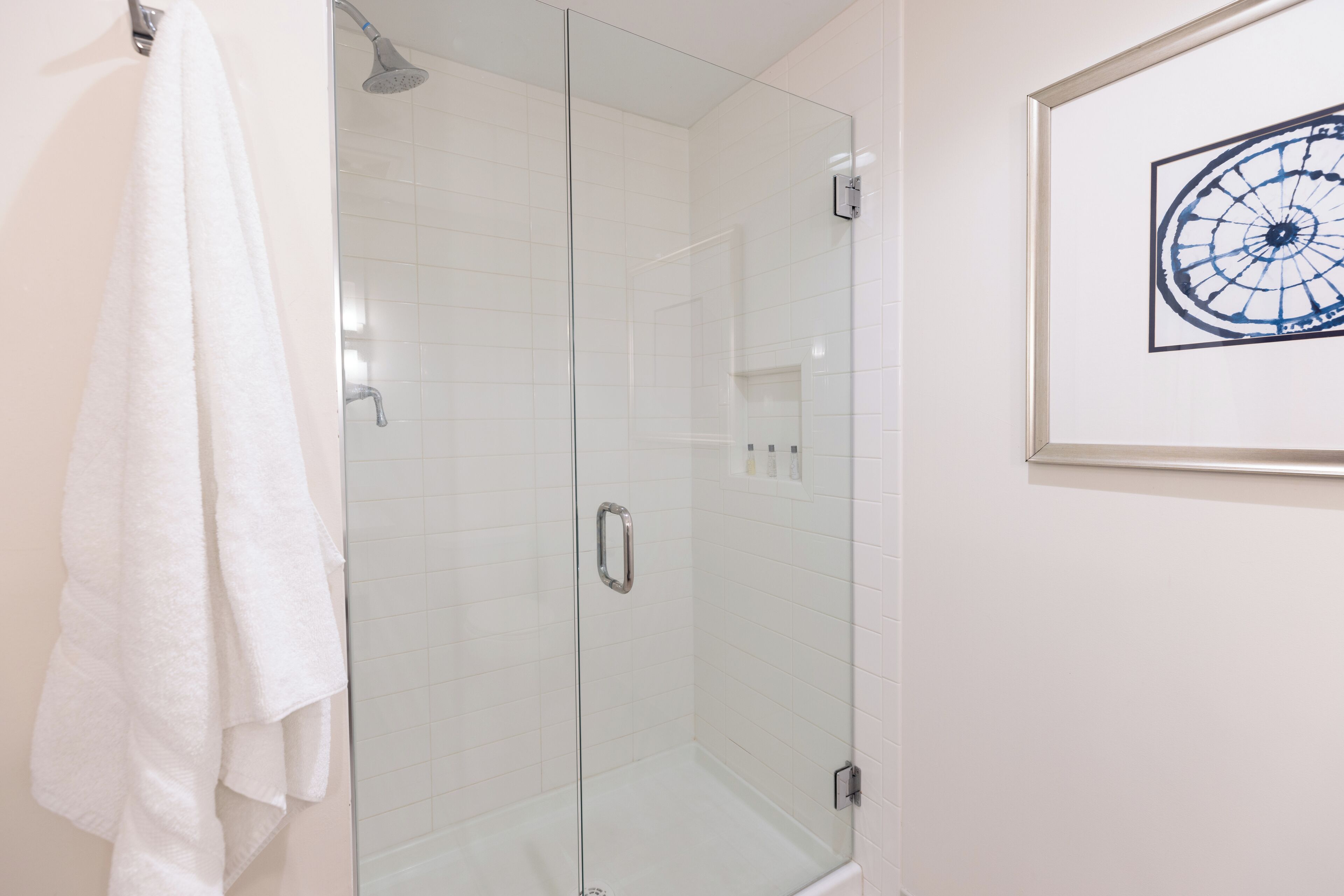 Eine begehbare Dusche mit Glaswänden und ein weißes Handtuch an der Wand.