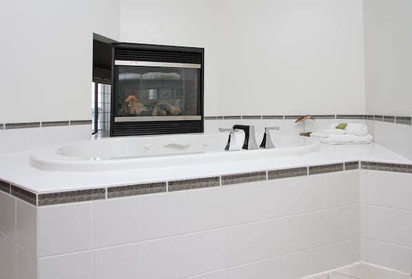 Un baño moderno con un lavamanos blanco, grifo negro y cabina de ducha con una pieza decorativa en su interior.