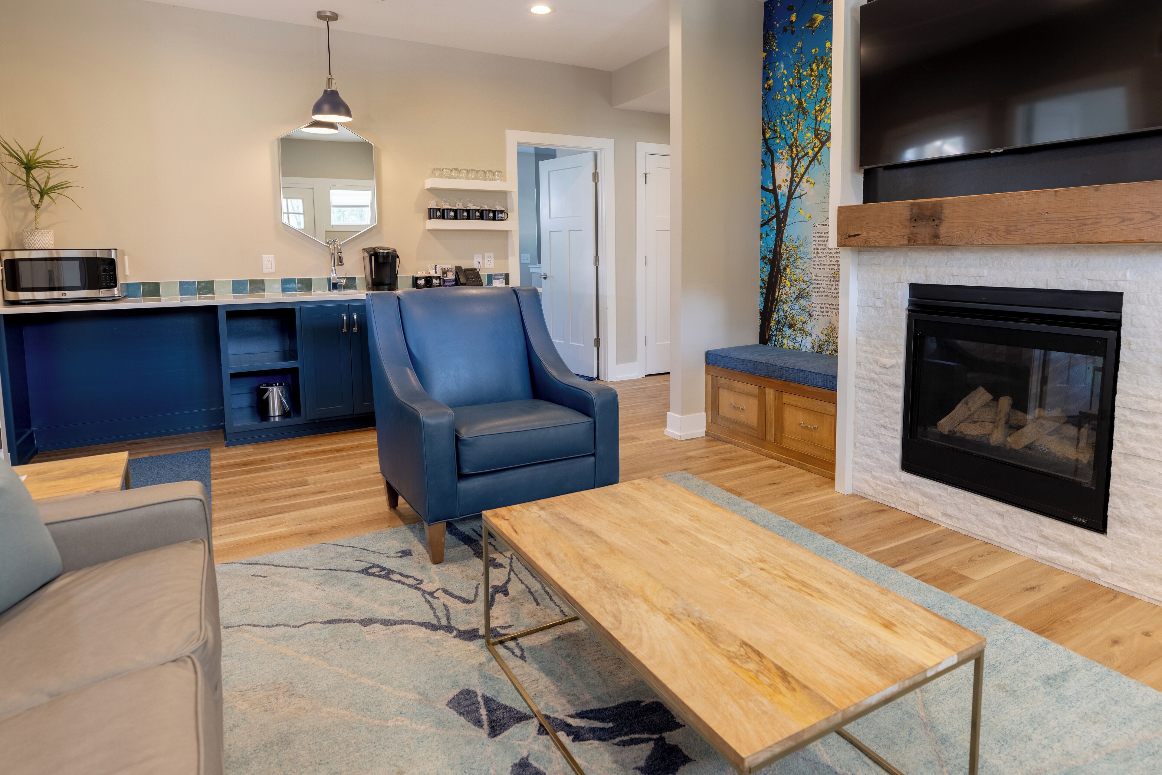 A modern living room with a blue armchair, a wooden coffee table, and a fireplace.