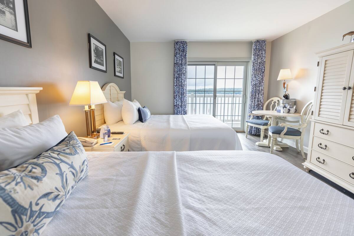 A hotel room with two beds, a desk, a chair, and a wardrobe.