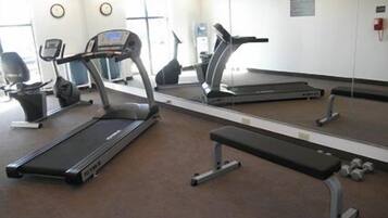 A gym with treadmills, a bench, and a mirrored wall.