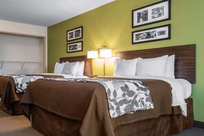 Habitación de hotel con dos camas, cabecero de madera, pared verde y cuadros enmarcados.